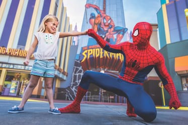 A girl fist bumps Spider-Man in front of the Spider-Man ride at Universal's Islands of Adventure.